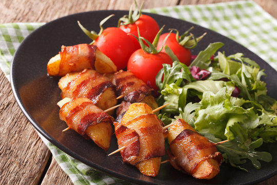 Fried potatoes wrapped in bacon and fresh salad close-up. horizontal