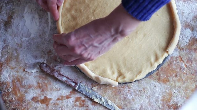 A woman is preparing an apple pie in a home kitchen