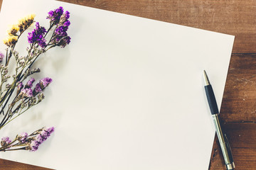 Dried flower with paper on wooden table