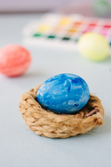 Deep blue easter egg on nest over bright background.
