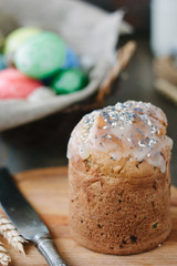 Easter cake standing on board against the basket with easter eggs.