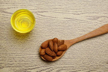 Almond oil in a glass bottle with almond on wooden background