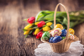 Easter. Hand made painted easter eggs in basket and spring tulips.