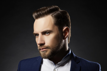 Portrait of handsome stylish caucasian young man in elegant blue suit with perfect hair style. 