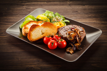 Grilled steak with toasted buns on wooden background