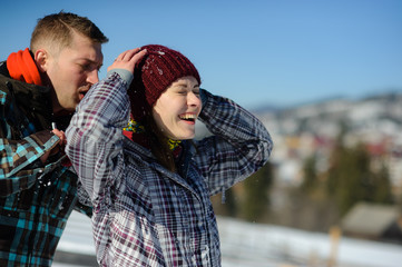 Young man carefully shakes snow from clothes of girlfriend.