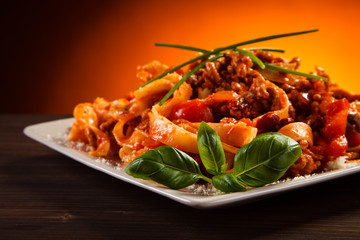Pasta with tomato sauce and vegetables on table