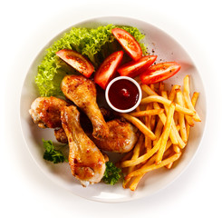 Grilled chicken legs with chips and vegetables