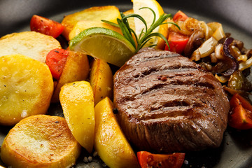 Grilled steak and potatoes on frying pan