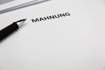 Mahnung mit Stift auf Blatt
