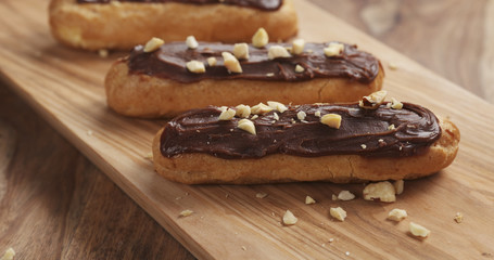 eclairs with hazelnuts on wood board, 4k photo