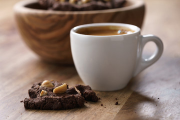 cup of fresh espresso with homemade chocolate cookie with hazelnuts, shallow focus