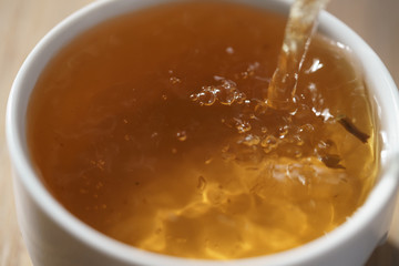 macro photo of pouring puerh tea in cup, shallow focus