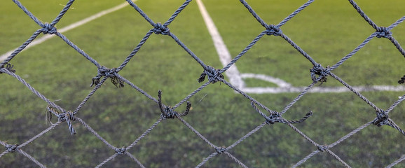 Fototapeta premium Front focus of the thin mesh fence barrier between us and the football field.