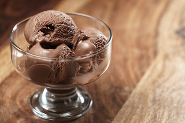 chocolate ice cream in glass bowl on wooden table, shallow focus