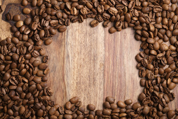 frame from roasted coffee beans on wood background, top view