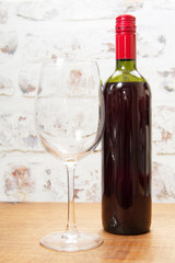 Bottle of red wine with glass ready to pour