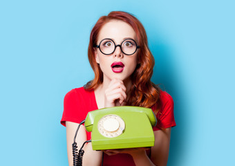 beautiful surprised young woman with retro phone on the wonderful blue background