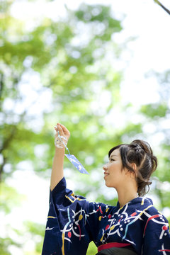 Young woman wearing Yukata and holding a wind chime