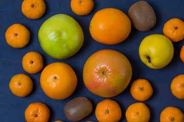 many beautiful bright juicy ripe delicious mouth-watering citrus fruits are are dark blue on a black background scattered freely close-up macro