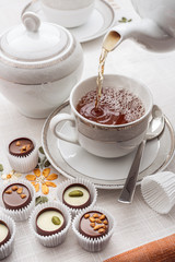 Tea in a white cup and chocolate candies.