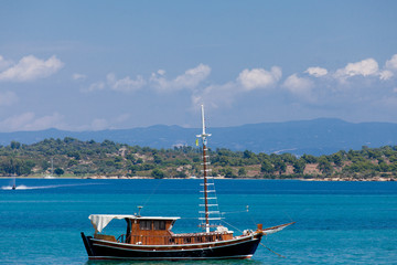 photo of cute fishing boat in front of wonderful sea and island background in Greece