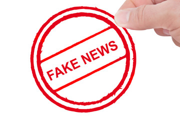 Fake News - Männliche Hand hält Aufkleber