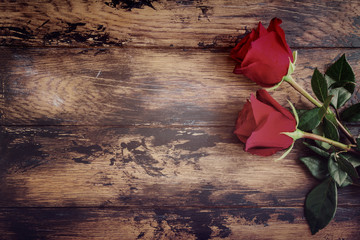 Obraz premium Fresh red rose flowers on the wooden background, dark horizontal boards, copy space, vintage, top view, flat lay.
