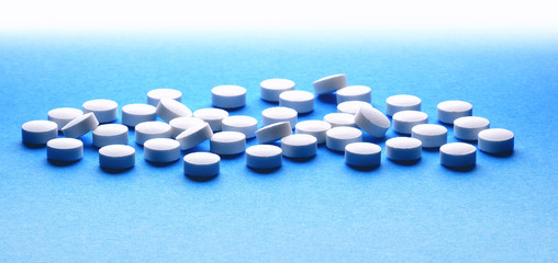 White pills on varied colour background 