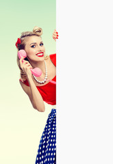 woman with phone, in pin-up style dress, showing blank signboard