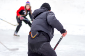 Fototapeta na wymiar Blurry sport background - boy attacking girl in hockey game