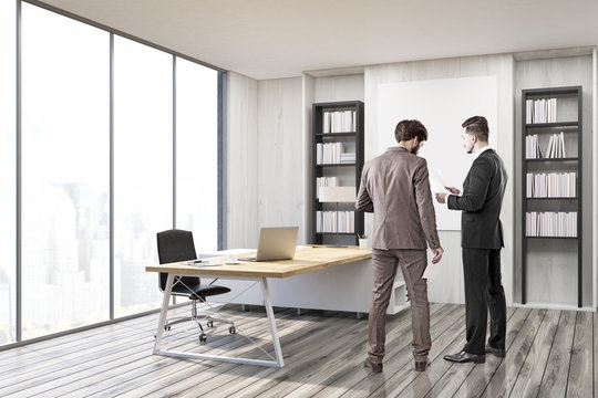 Two men in suits in CEO office with gray walls