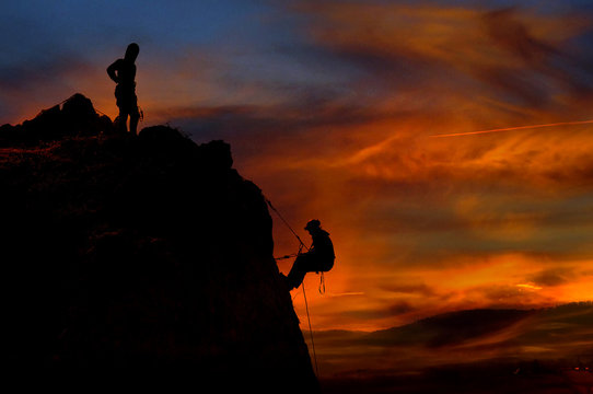 Climber waiting his partner on the summit. Beautiful sunset in the background