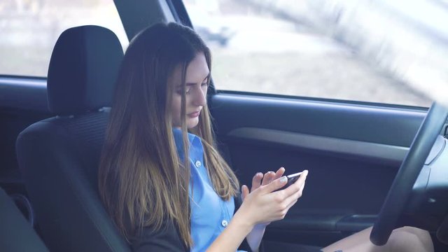 Profile of emotional girl sitting in the car and using smartphone