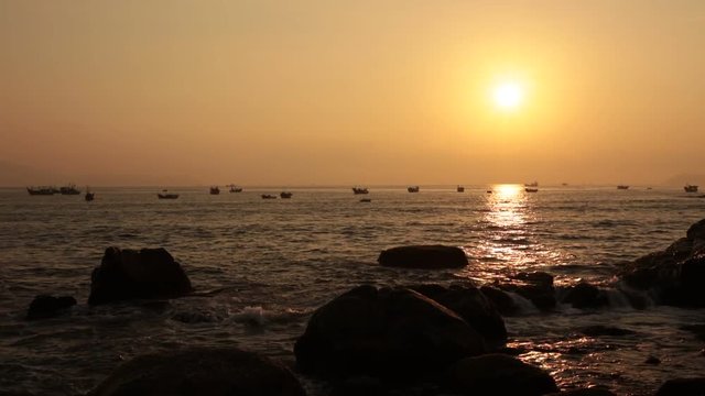 A sunrise over the south China sea in Vung Lam Bay Vietnam with fishing boats coming and going.
