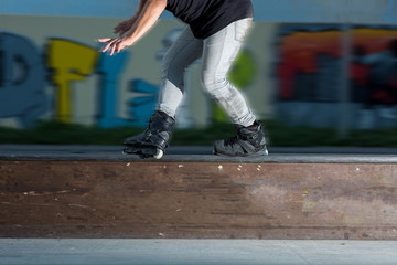 Young man rollerblading. Rollerblader near graffiti. Not afraid of speed. Legs of person on inline...