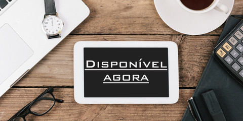 Disponível agora, Portuguese text for Available Now on screen of tablet computer at office desk