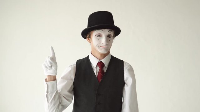 man mime standing on white background and looking to the camera. Finger waves side to side to express "no" or "tsk tsk."
