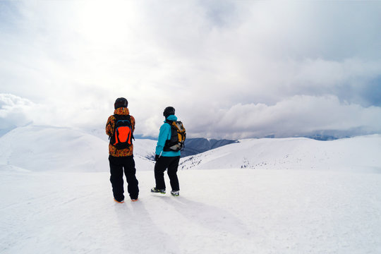 two freeriders on mountain peak looking for perfect line in powder
