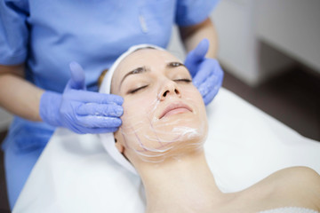 Fototapeta na wymiar Beautiful woman at spa salon, Cosmetician woman applying facial mask.