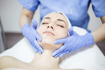 Obraz na płótnie Canvas Beautiful woman at spa salon, Cosmetician woman applying facial mask.
