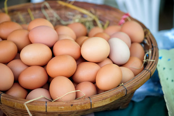 Eggs in a basket weave on market organic vegetables.