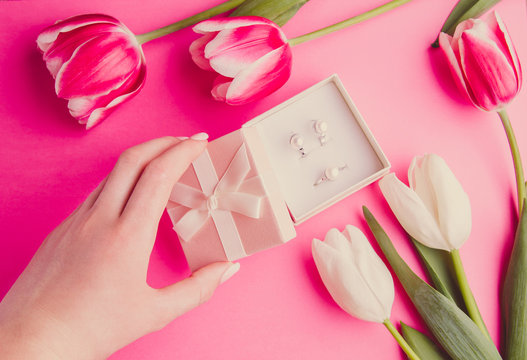 Woman's hand opening a box with jewellery surrounded with tulips