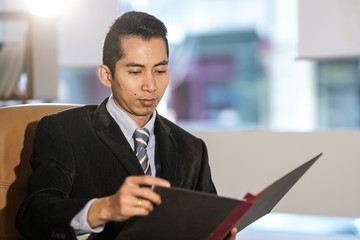 Fototapeta premium Thai white collar worker posing at desk in office reading documents