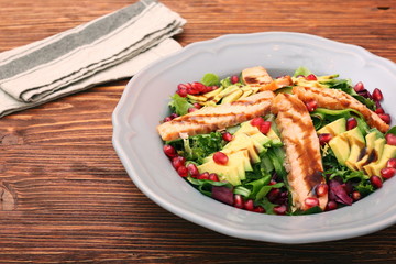 Salad with fried salmon, avocado and pomegranate seeds. Low fat healthy eating concept.