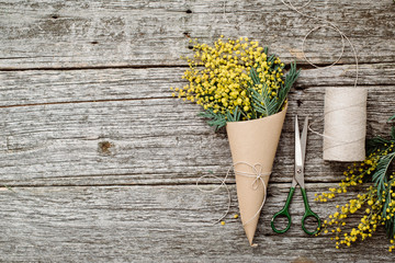 Make bouquet of mimosa. bandages twine and scissors on rustic wooden table