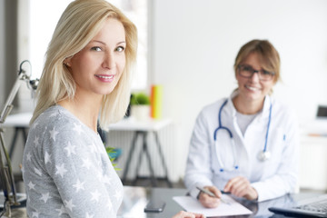 Doctor and her patient. Shot of a middle aged smiling female doctor sitting in front of laptop and meeting with her patient.