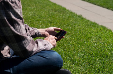 Man sitting on grass using phone