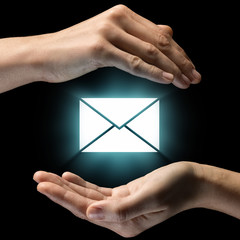 Isolated image of two hands on black background. Envelope icon in the center, as a symbol of...