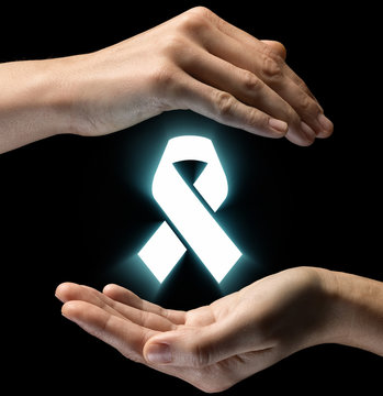 Isolated image of two hands on black background. Ribbon icon in the center, as a symbol of care for HIV and cancer patients. Concept of care for HIV and cancer patients.